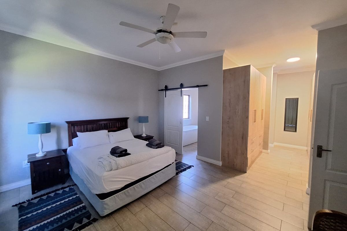 Spacious bedroom featuring tiled flooring, a ceiling fan, built-in wardrobes, and a sliding barn door leading to an en-suite bathroom.