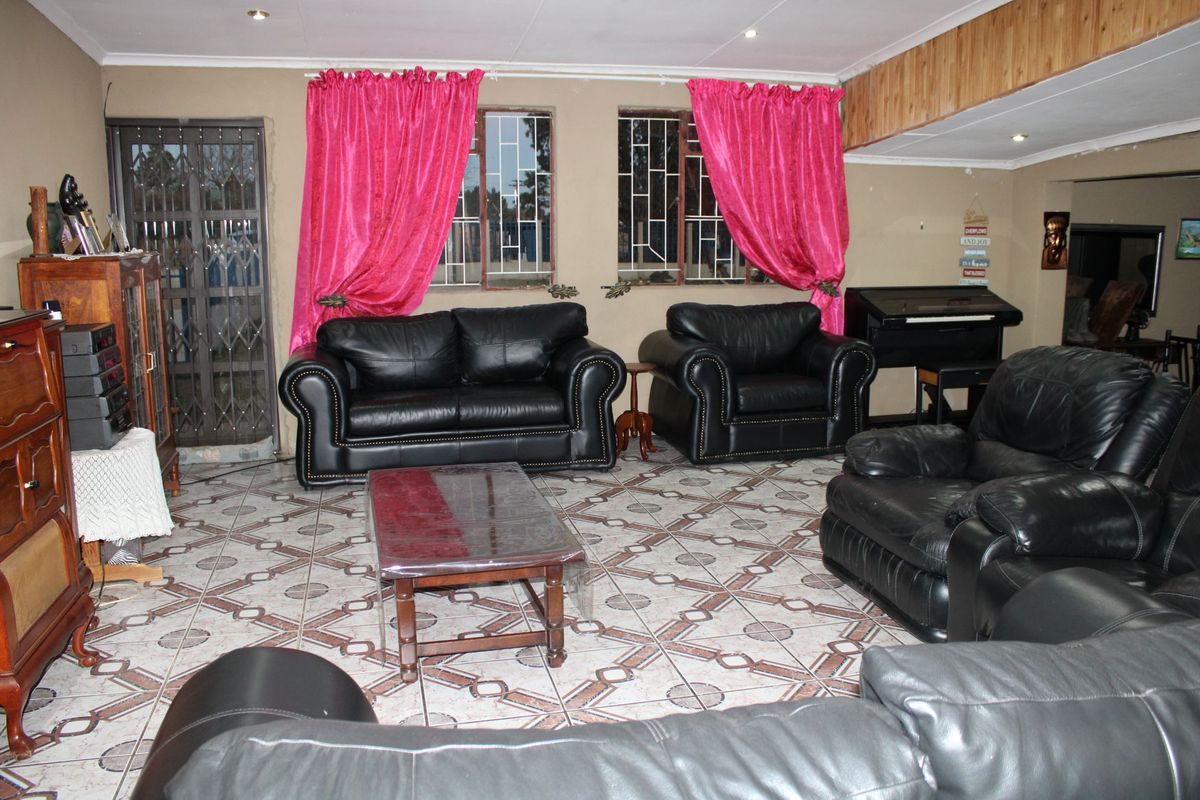 Spacious living room featuring tiled flooring, recessed lighting, and security features including burglar bars and a metal security gate.