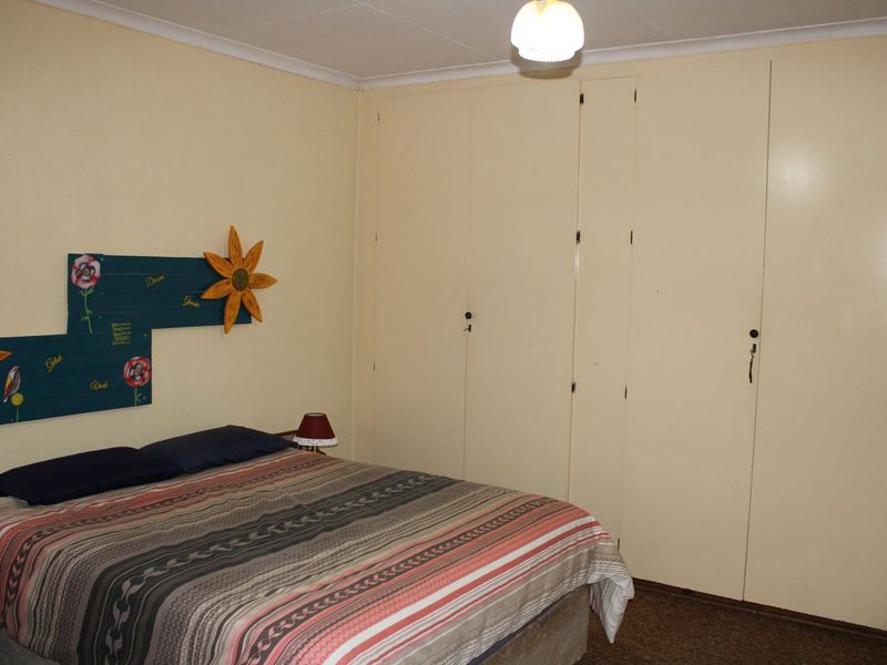 A bedroom featuring built-in cupboards and coved ceiling details, offering a functional space with neutral wall finishes.