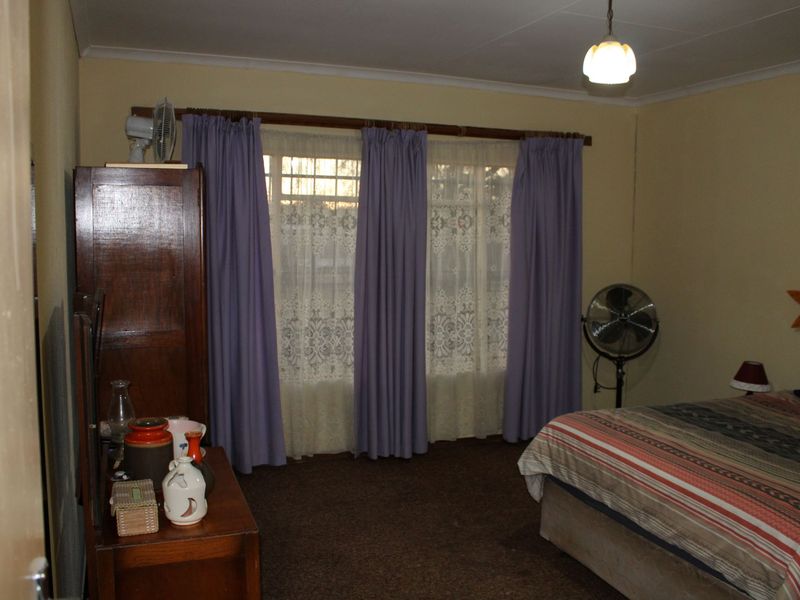 A standard bedroom featuring carpeted flooring and large windows with curtain rails, providing a functional space for rest.