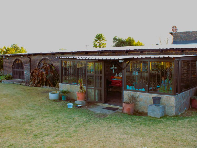 Enclosed patio area featuring brick construction and tiled base, providing a versatile outdoor living space overlooking the garden.