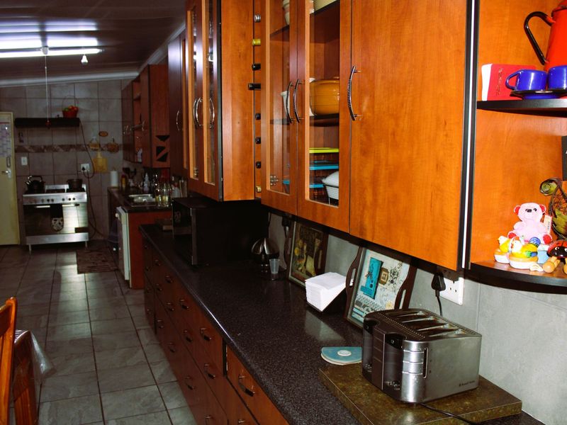 A functional kitchen featuring extensive wooden cabinetry, dark granite countertops, and stainless steel appliances with tiled flooring throughout.