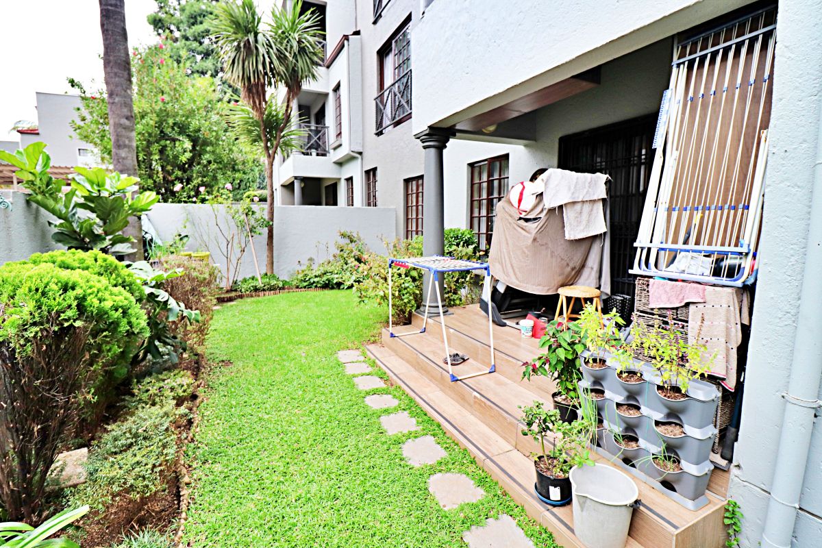 A ground floor apartment featuring a private tiled patio area leading onto a small, well-maintained garden space.