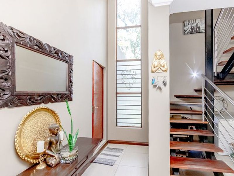 Welcoming entrance hall featuring double-volume windows, tiled flooring, and a modern timber staircase with stainless steel balustrades.
