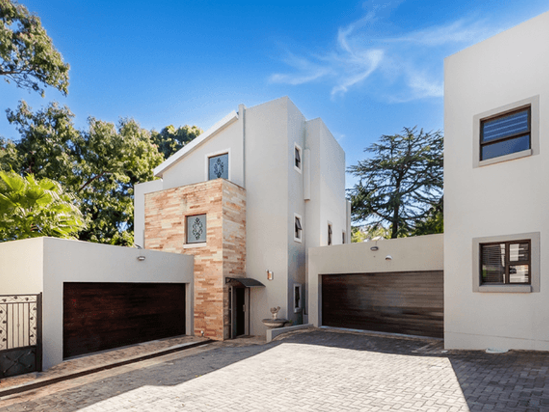 Modern townhouse exterior featuring a paved driveway, double garage, and attractive stone cladding accents on the front facade.