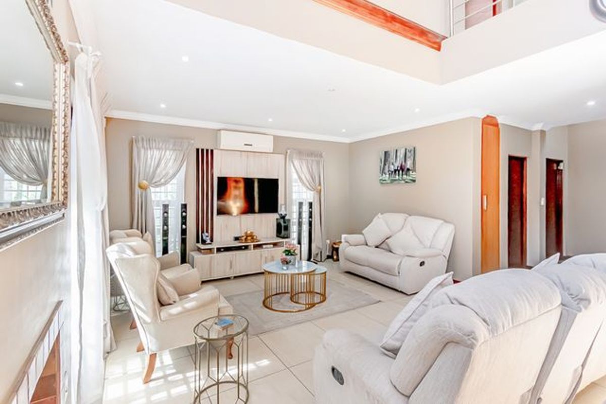 Spacious living room featuring double-volume ceilings, tiled flooring, recessed lighting, and a built-in media unit with an integrated air conditioning system.