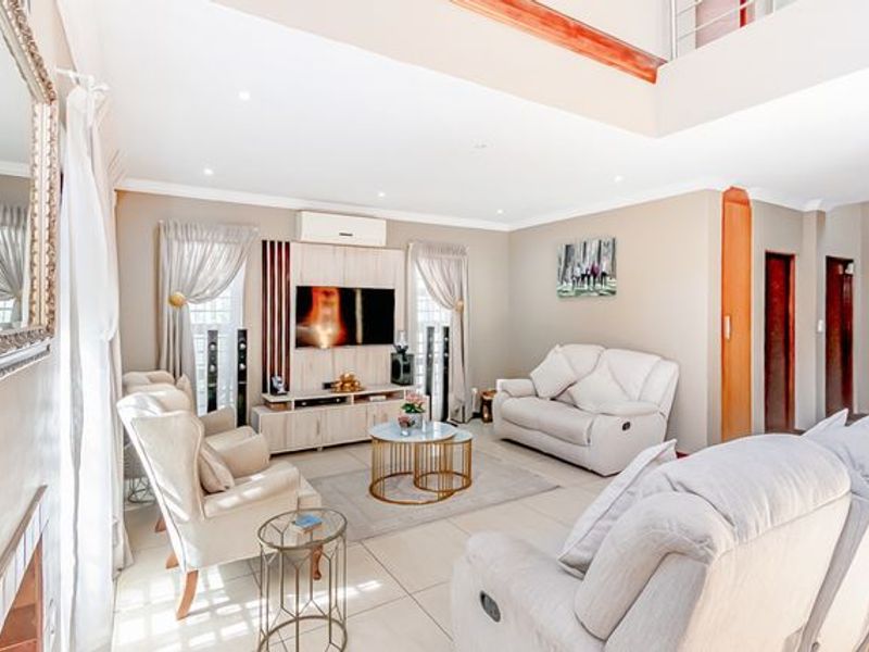 Spacious living room featuring double-volume ceilings, tiled flooring, recessed lighting, and a built-in media unit with an integrated air conditioning system.
