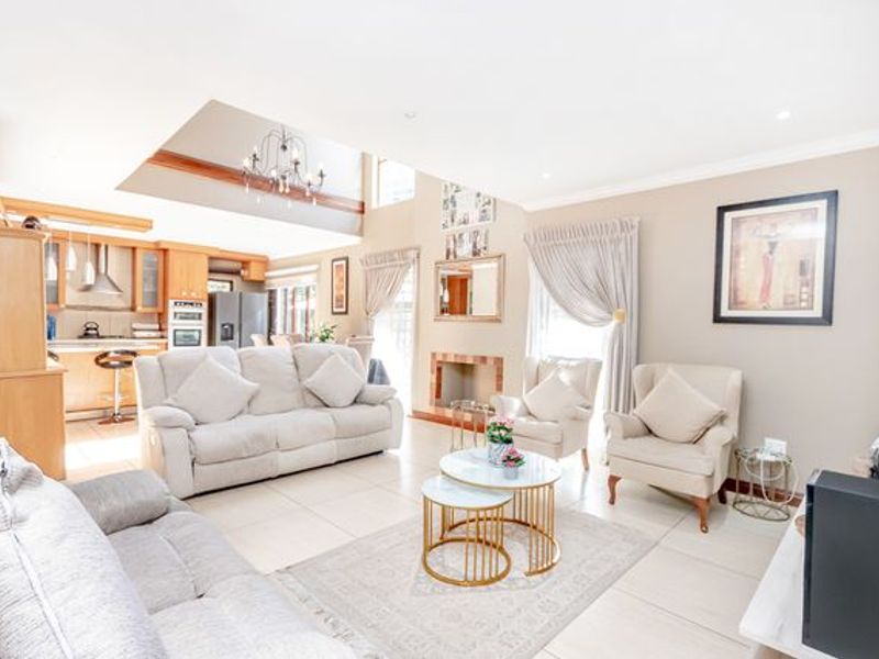 Spacious open-plan living area featuring a modern kitchen with built-in appliances, a cozy fireplace, and tiled flooring throughout.