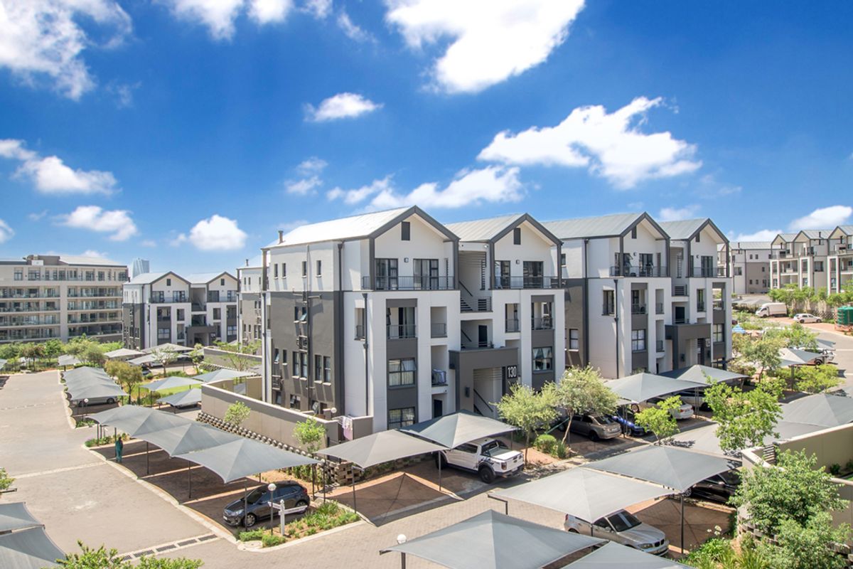 Aerial view of a modern multi-story apartment complex featuring covered parking bays and well-maintained exterior facades.
