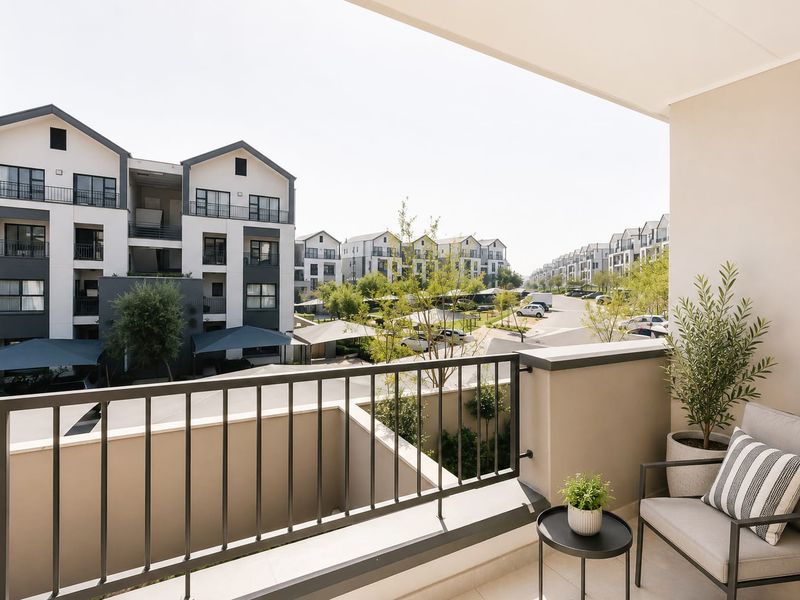 A modern covered balcony featuring a metal balustrade and tiled flooring, offering an elevated view of the surrounding residential complex.