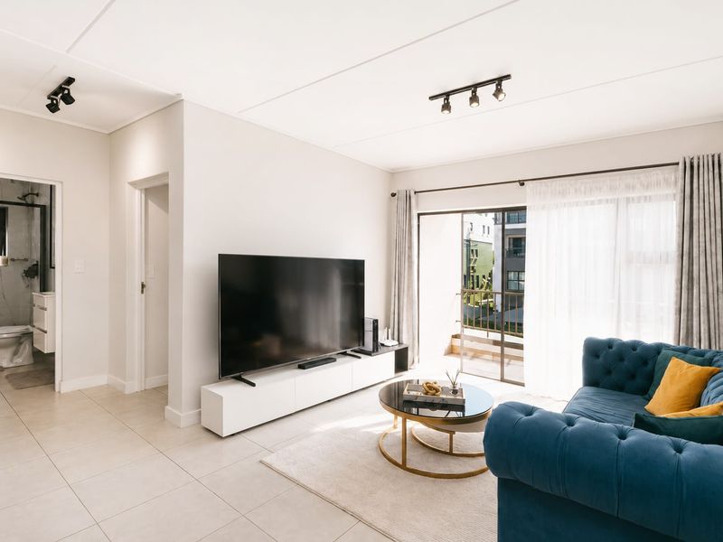 Bright living room featuring tiled floors, modern track lighting, and a sliding glass door providing direct access to a private balcony.