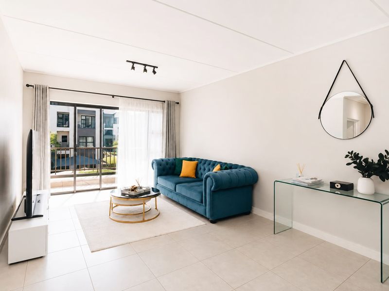 Bright and modern living room featuring neutral tiled flooring, track lighting, and large sliding glass doors providing access to a private balcony.