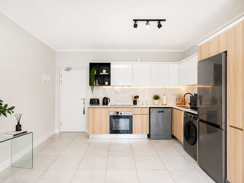 Modern kitchen featuring light wood and white cabinetry, marble-look splashback, integrated appliances, and sleek tiled flooring.