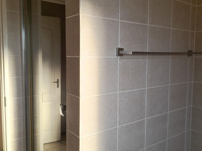 A functional bathroom featuring tiled walls, a shower enclosure, and a built-in bathtub with a wall-mounted towel rail.