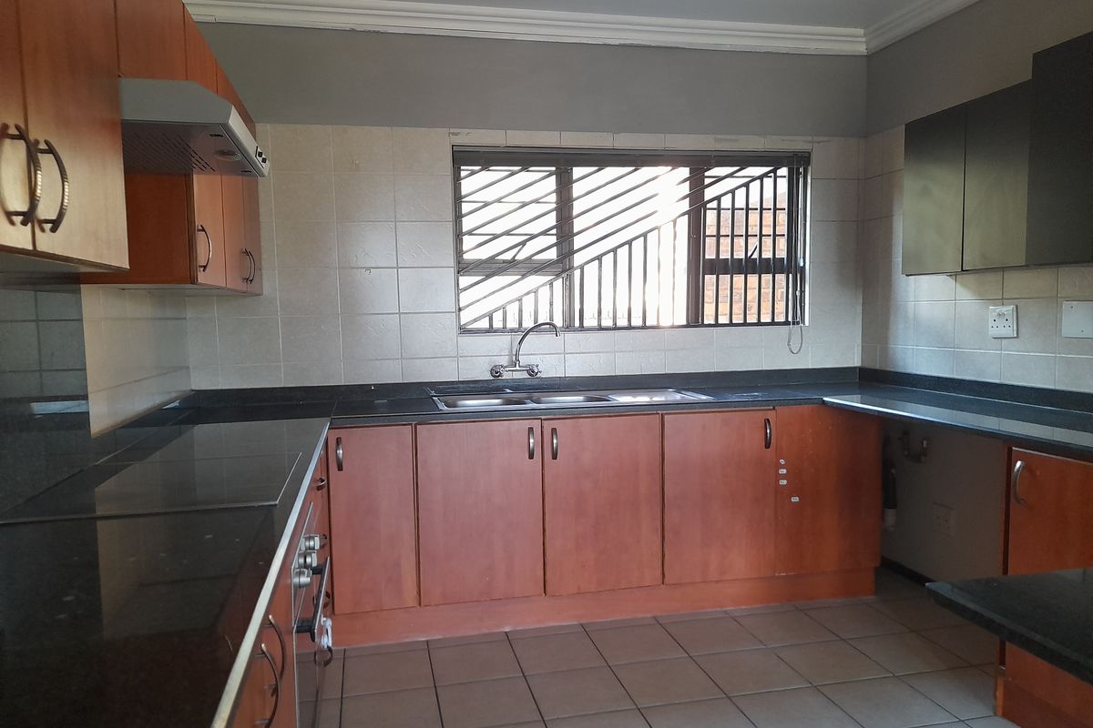 Functional kitchen featuring wooden cabinetry, granite countertops, built-in oven and hob, tiled backsplash, and tiled flooring.