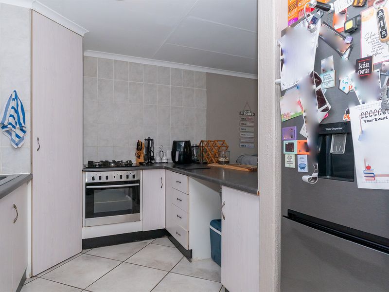 Compact kitchen featuring built-in oven, gas hob, tiled splashback, and laminate cabinetry with tiled flooring.