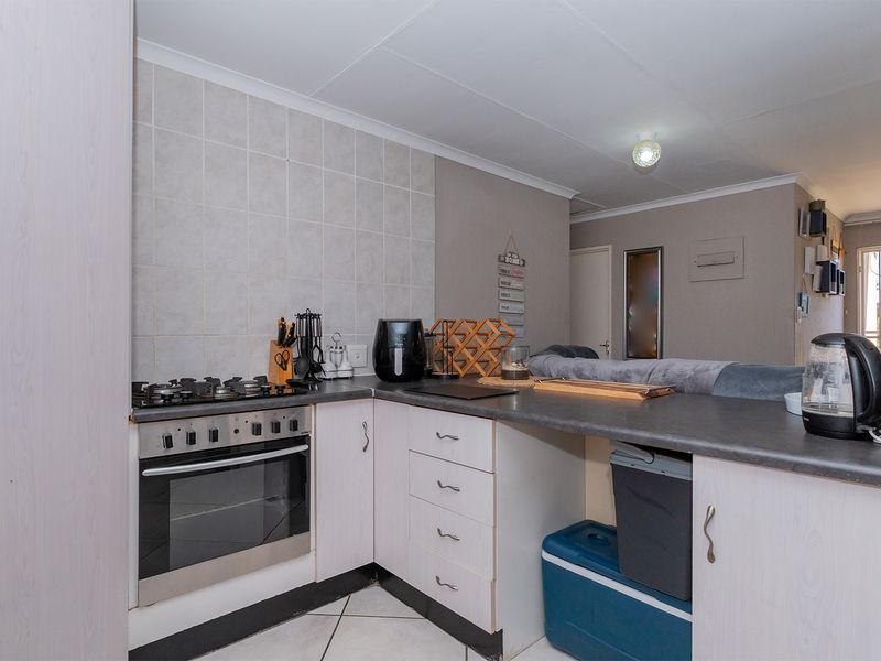 Compact kitchen featuring built-in oven, gas hob, tiled splashback, and laminate cabinetry with a breakfast bar counter.