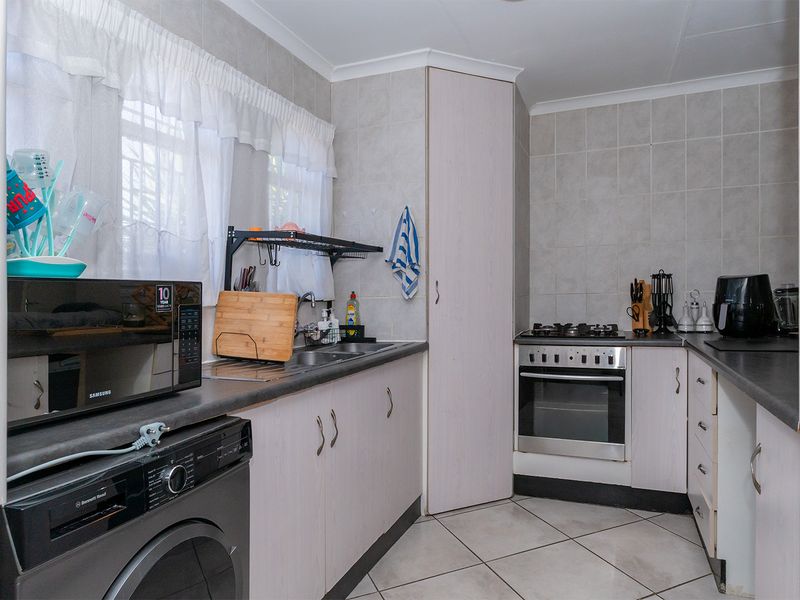 Functional kitchen featuring built-in cabinetry, laminate countertops, a gas stove with oven, and tiled finishes throughout.