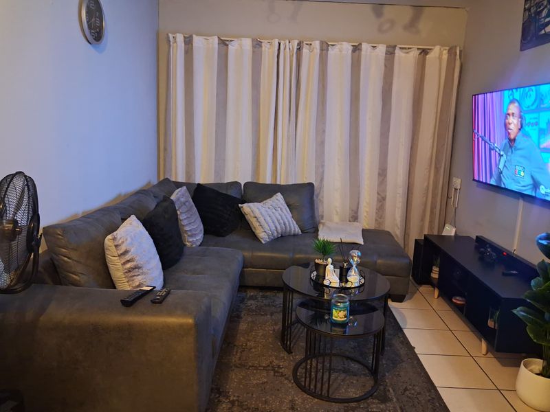 A functional living room featuring tiled flooring and neutral wall finishes, providing a comfortable space for relaxation.