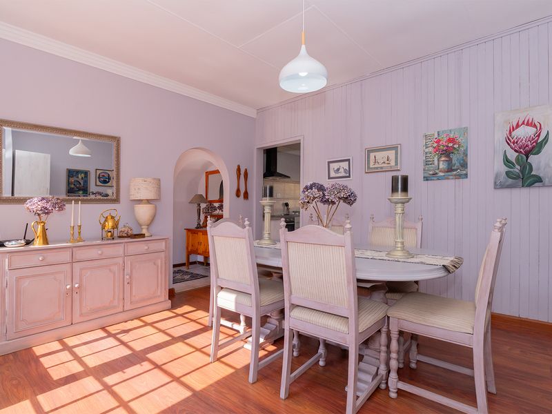 A well-maintained dining room featuring laminate flooring, coved ceilings, and a classic archway leading to the kitchen area.