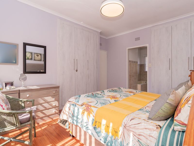 A well-maintained bedroom featuring laminate flooring, ample built-in cupboard storage, and direct access to an en-suite bathroom.