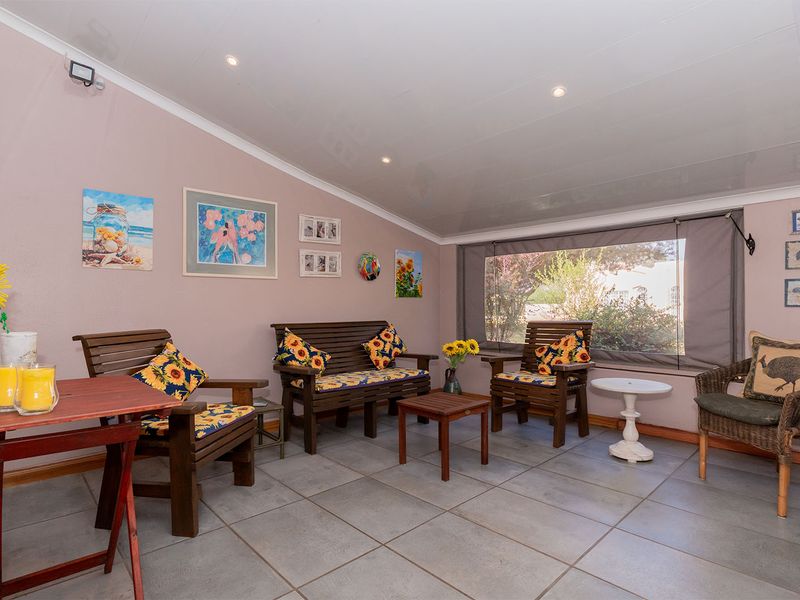 A covered patio area featuring tiled flooring, recessed downlighting, and a roll-up outdoor blind, providing a comfortable space for relaxation.