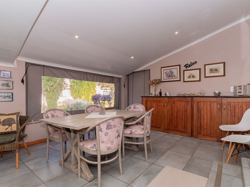 Enclosed patio area featuring tiled flooring, built-in wooden cabinetry, and roll-up canvas blinds, providing a versatile space for dining or relaxation.