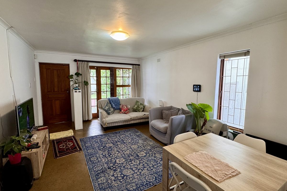 A functional living area featuring timber doors, security window bars, and direct access to the outdoor space.
