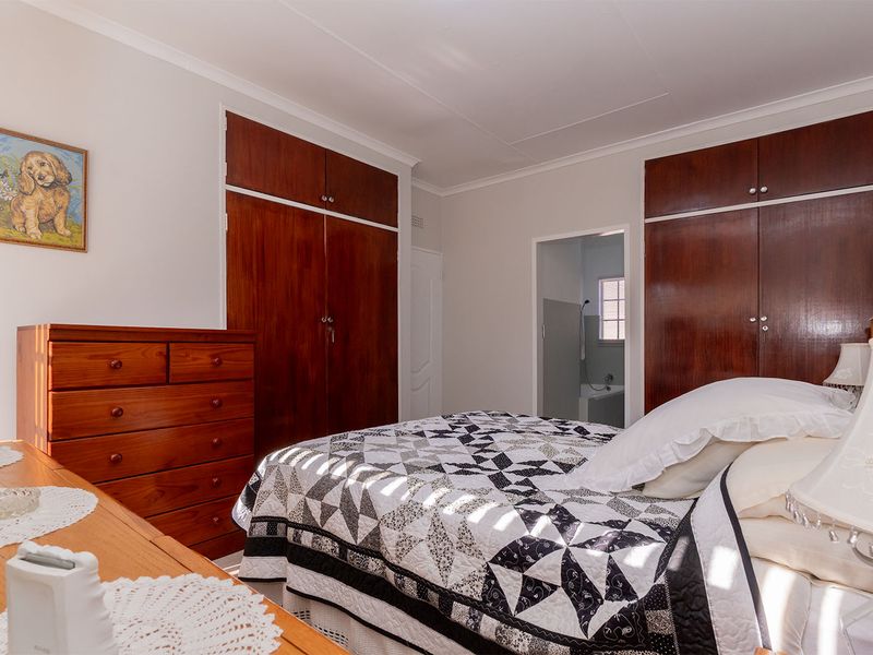 A bedroom featuring built-in wooden cupboards and direct access to an en-suite bathroom, offering a functional layout with classic finishes.