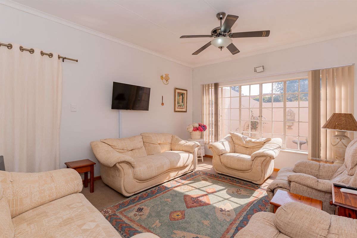 A comfortable living room featuring a ceiling fan and a large window that allows for natural light, creating a bright and inviting space.