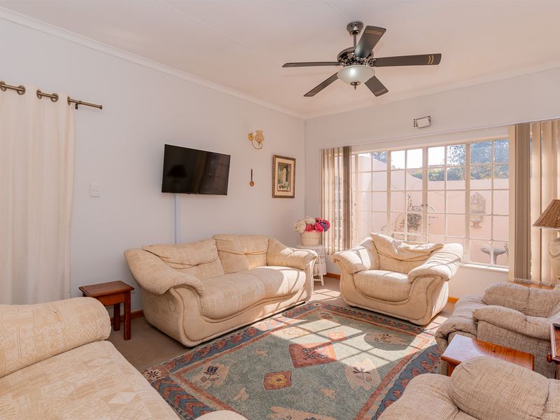 A comfortable living room featuring a ceiling fan and a large window that allows for natural light, creating a bright and inviting space.