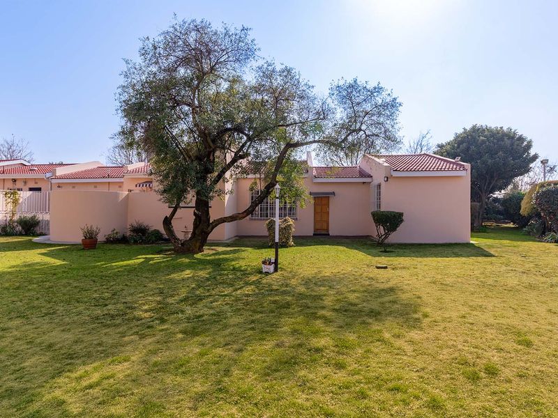 A view of the rear exterior of the apartment, featuring a private garden, mature tree, and tiled roof structure.