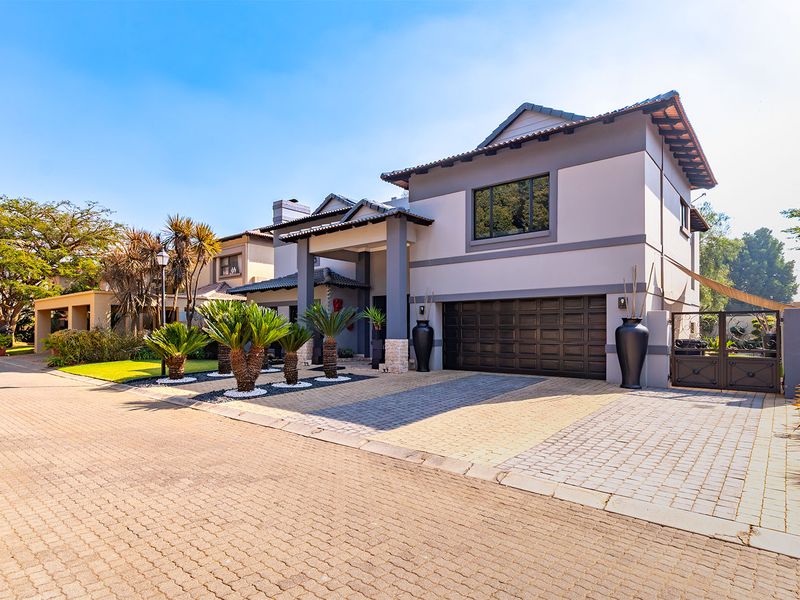 A well-maintained double-story residential property featuring a paved driveway, double garage, and modern architectural finishes with stone cladding accents.