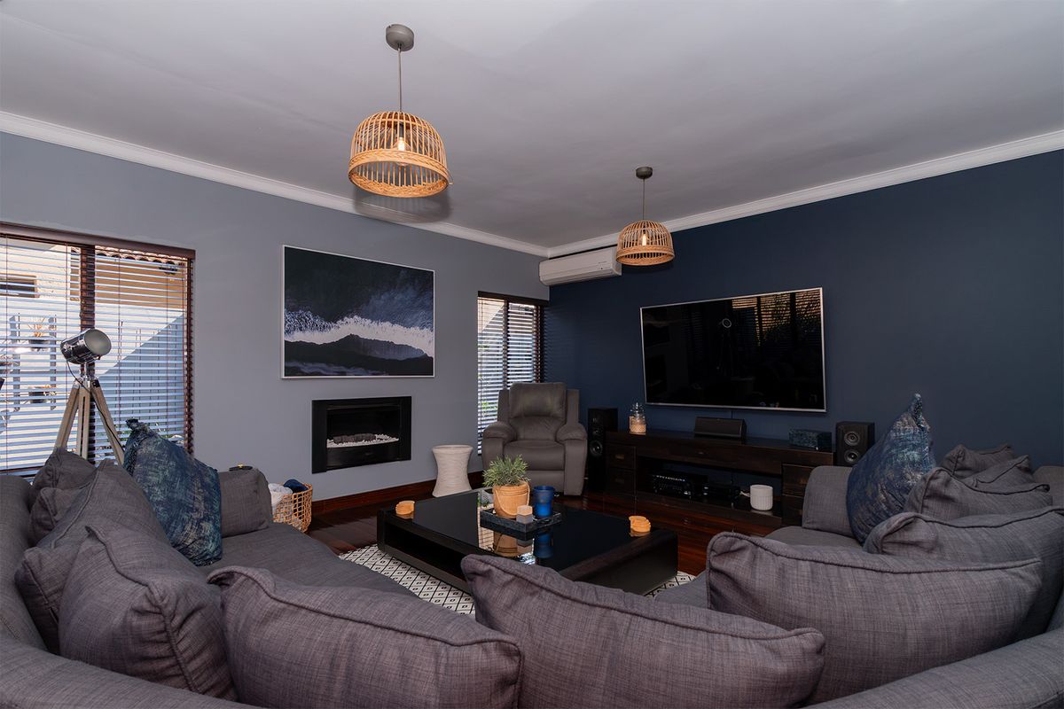 A well-maintained living room featuring dark hardwood floors, a built-in fireplace, split-system air conditioning, and modern accent walls.