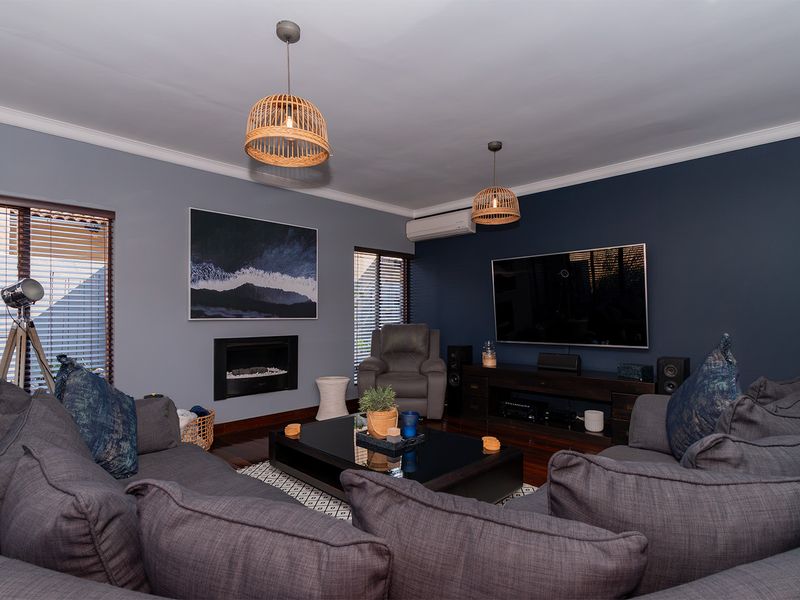A well-maintained living room featuring dark hardwood floors, a built-in fireplace, split-system air conditioning, and modern accent walls.