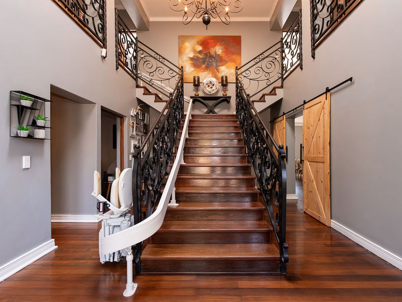 Grand entrance hall featuring a central timber staircase with ornate wrought iron balustrades, hardwood flooring, and a sliding barn door.