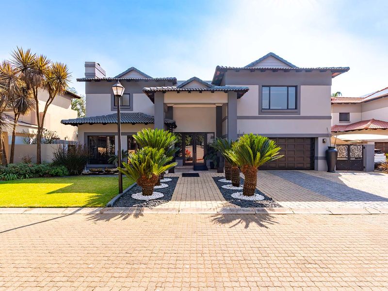 A well-maintained double-story residential property featuring a paved driveway, double garage, covered entrance, and landscaped front garden.
