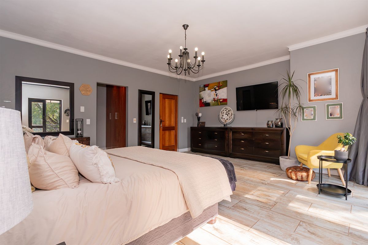 A spacious bedroom featuring tiled flooring, built-in cupboards, and a decorative chandelier, offering a well-maintained and comfortable living space.