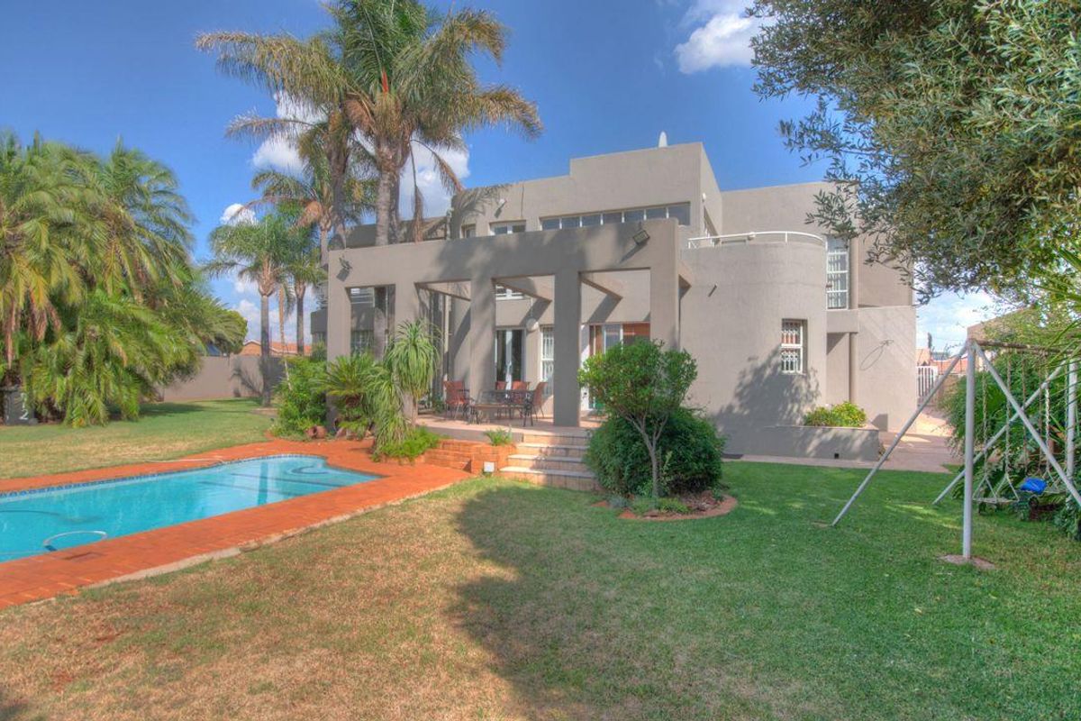 Rear view of the property featuring a spacious garden, a swimming pool, and a covered patio area perfect for outdoor entertaining.