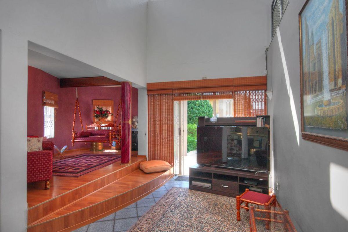 Spacious living area featuring a raised timber platform, high vaulted ceilings, and direct access to the outdoor patio through sliding glass doors.
