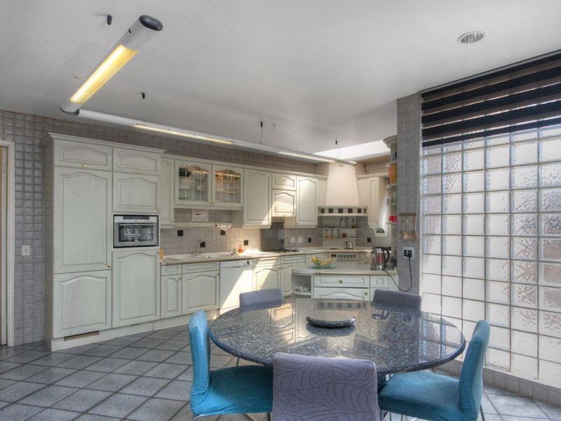Spacious kitchen featuring classic cabinetry, integrated appliances, tiled flooring, and a unique glass block wall providing natural light.
