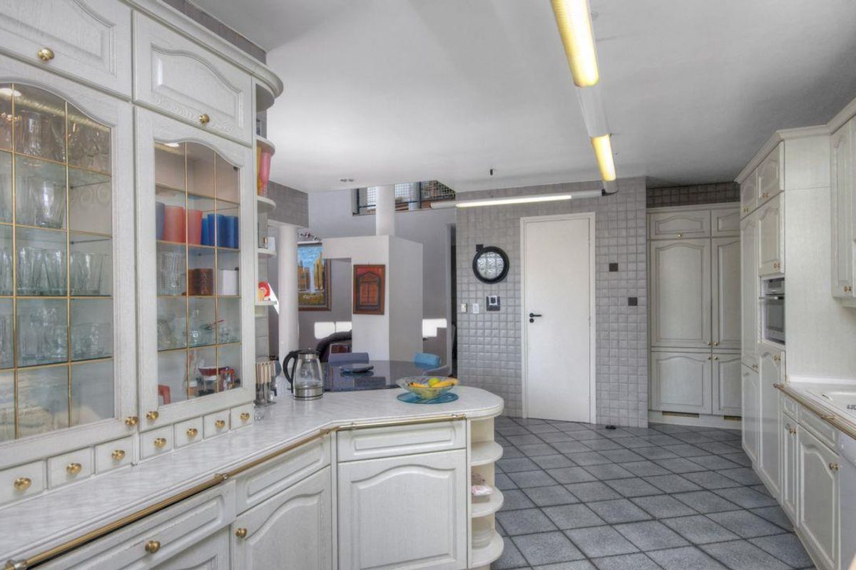 Spacious kitchen featuring extensive built-in cabinetry, tiled flooring, and a functional layout with integrated appliances and ample storage space.