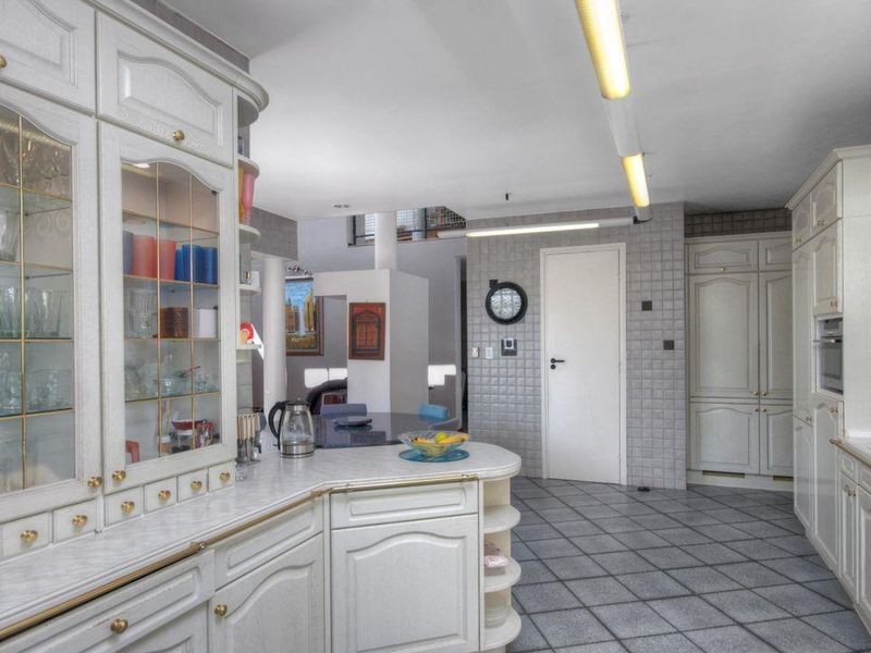 Spacious kitchen featuring extensive built-in cabinetry, tiled flooring, and a functional layout with integrated appliances and ample storage space.