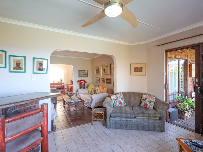 Open plan living area featuring tiled flooring, a ceiling fan, and an archway leading to an adjacent space with access to an outdoor patio.