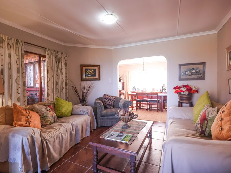 A comfortable living room featuring tiled flooring and an open archway leading to the dining area, with access to an outdoor patio.