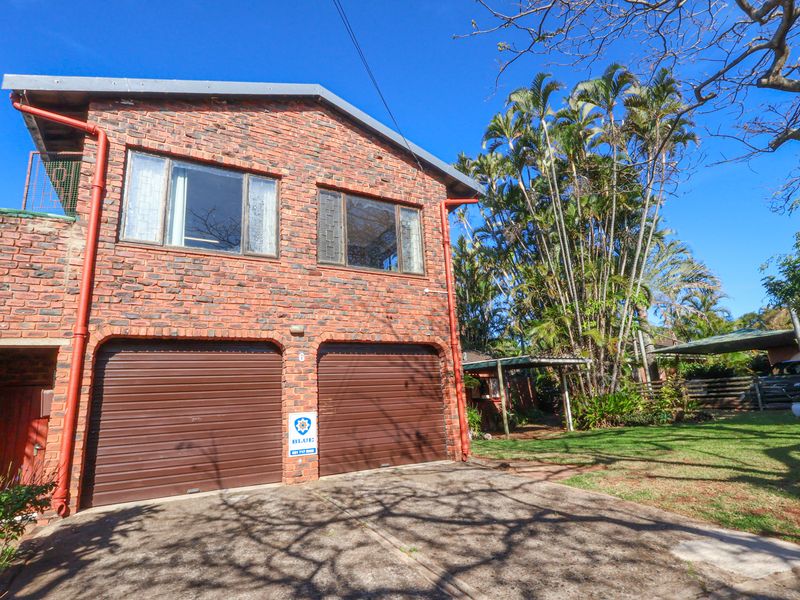 Front elevation of a double-storey brick house featuring a double garage with roller shutter doors and a paved driveway.