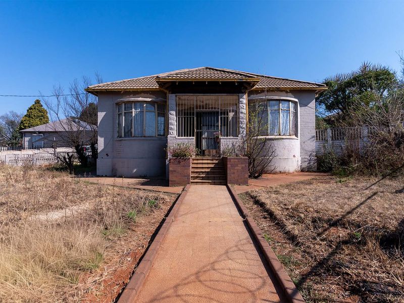 Front elevation of a single-story house featuring a tiled roof, bay windows, and a paved walkway leading to the entrance.