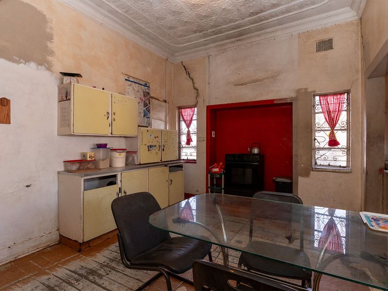 A dated kitchen featuring original pressed metal ceilings, requiring significant renovation and cosmetic updates to restore its functionality and aesthetic appeal.