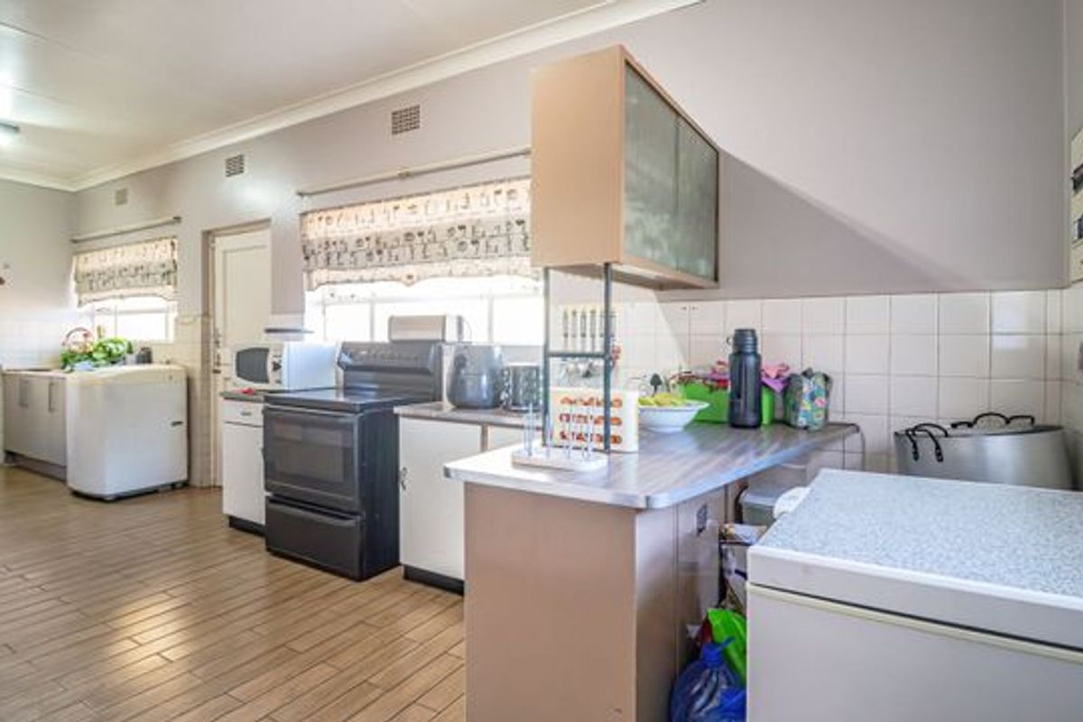 A functional kitchen featuring tiled flooring, built-in cabinetry, a tiled backsplash, and a freestanding stove, offering a practical layout with potential for modernization.