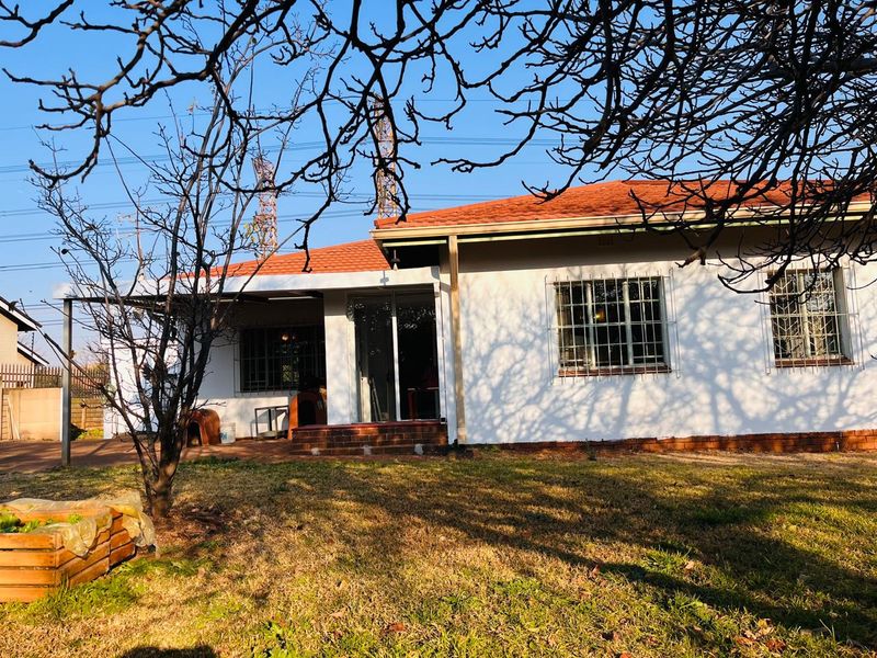 Rear view of the house featuring a covered patio, terracotta tiled roof, and security-barred windows overlooking the garden.